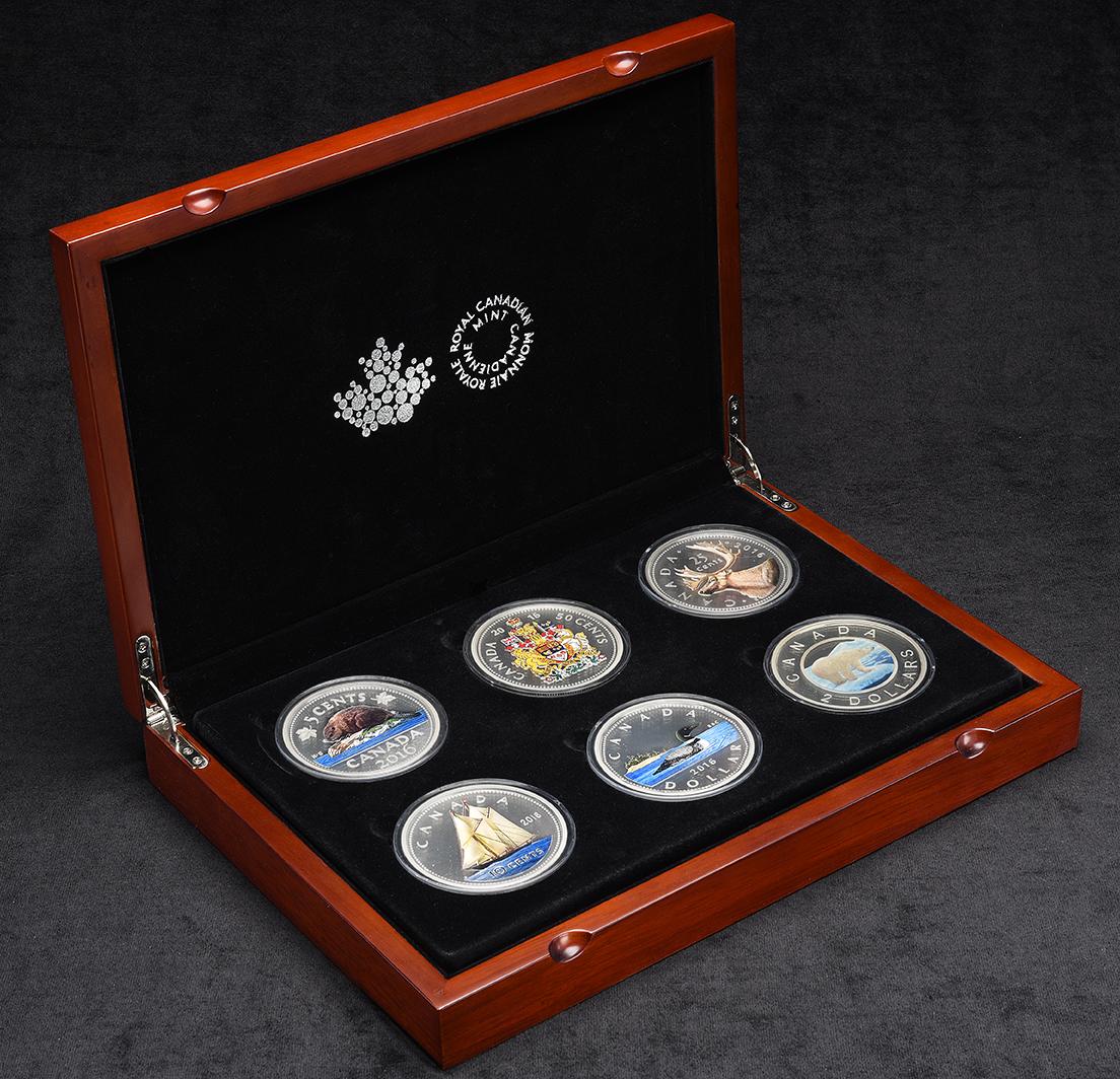 Coffret en bois ouvert, doublé de velours noir et contenant 6 pièces canadiennes colorées surdimensionnées.