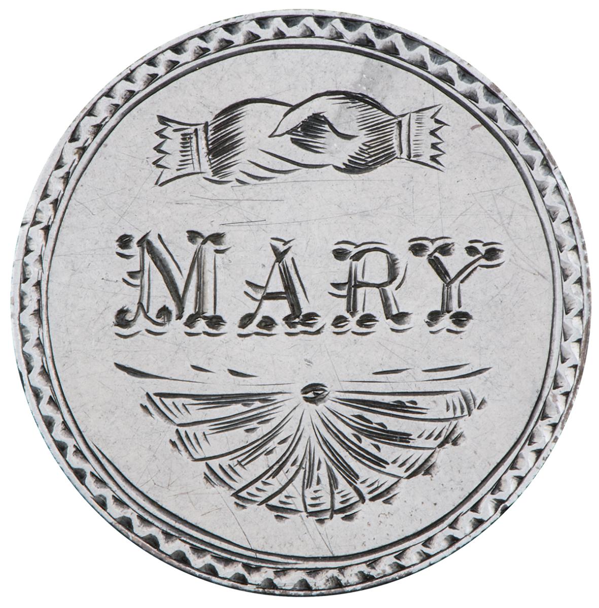 Pièce d’argent polie sur laquelle sont gravés le mot Mary, une poignée de main et un motif en éventail.