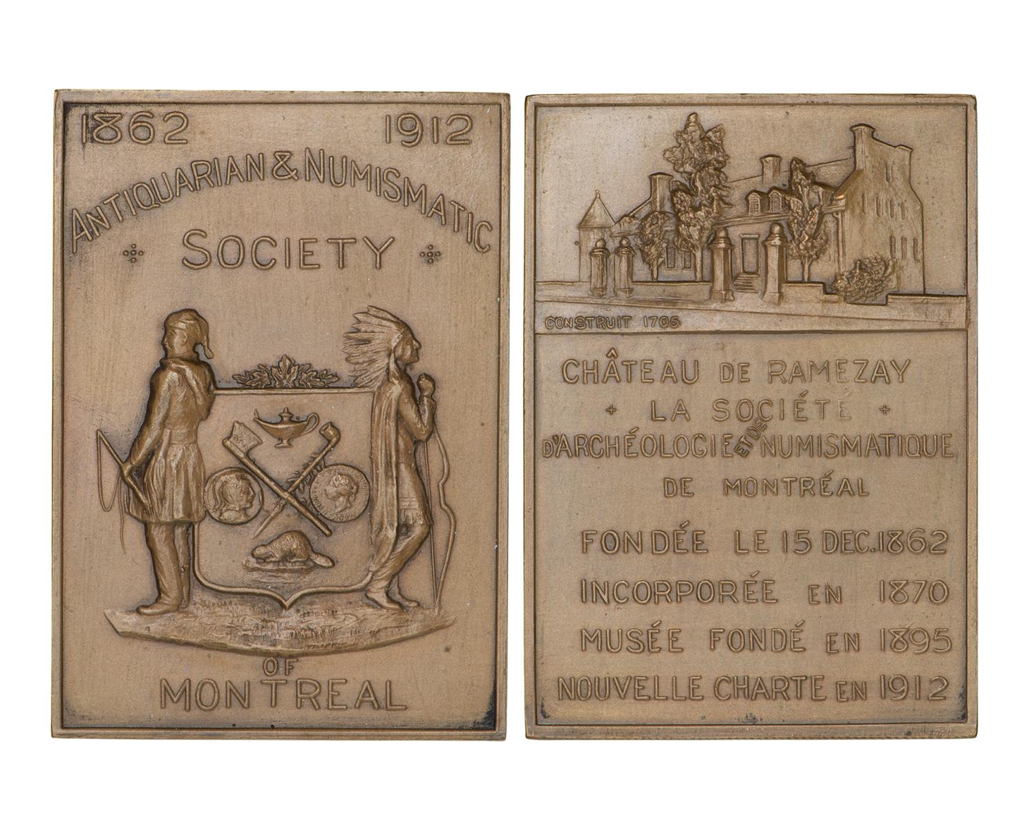 Médaille rectangulaire verticale, avec des armoiries d’un côté, et une vieille demeure et de nombreux mots de l’autre.