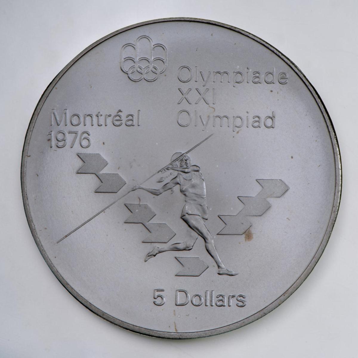 Pièce d’argent montrant une athlète qui court et lance une longue perche, des symboles en forme de flèches l’entourent.