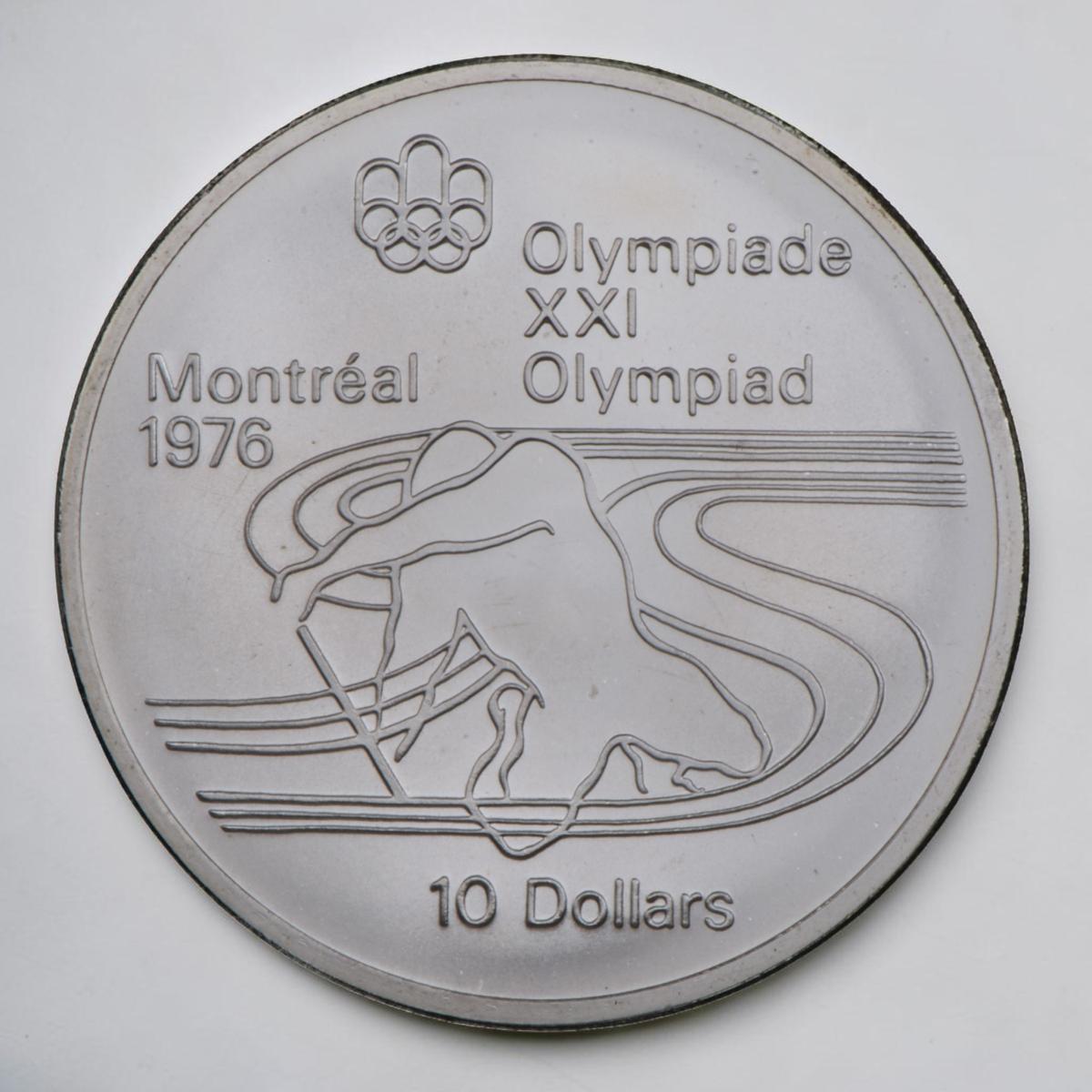 Pièce d’argent montrant la silhouette stylisée d’un athlète agenouillé et pagayant à l’intérieur de lignes fluides.