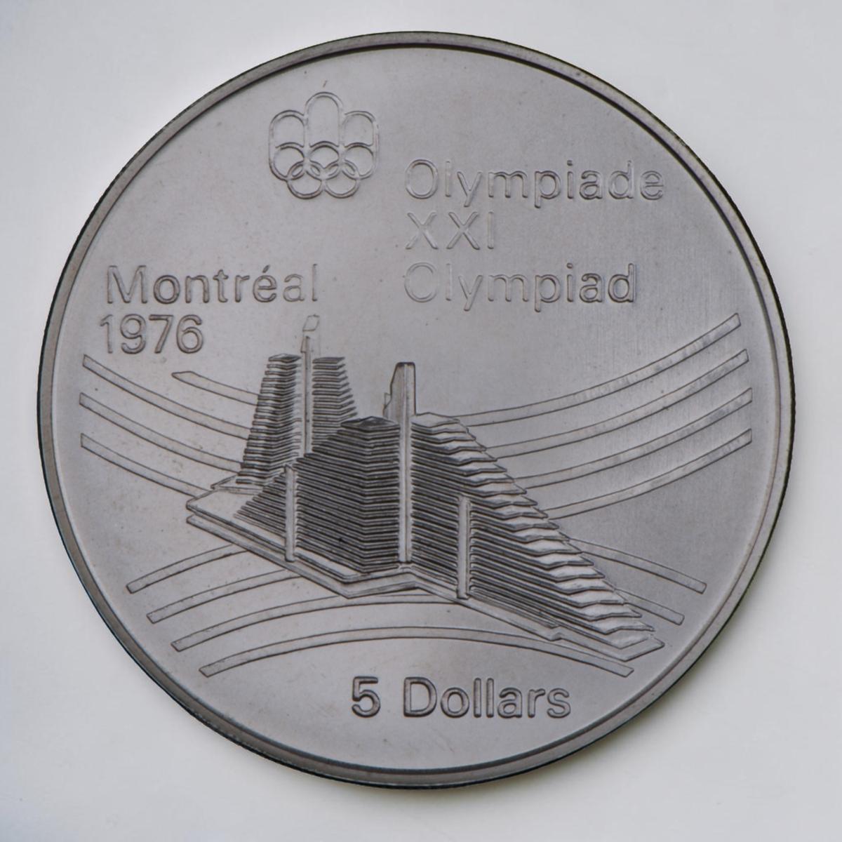 Pièce d’argent montrant deux hauts bâtiments triangulaires étroits avec des lignes courbées en arrière-plan.