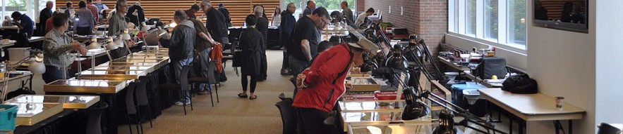 Salle où des gens installés à des tables vendent des pièces de monnaie et des billets de banque