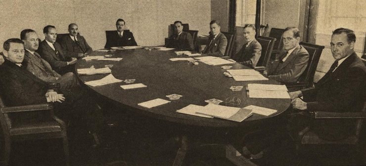 photographie en noir et blanc d’hommes autour d’une table de conseil