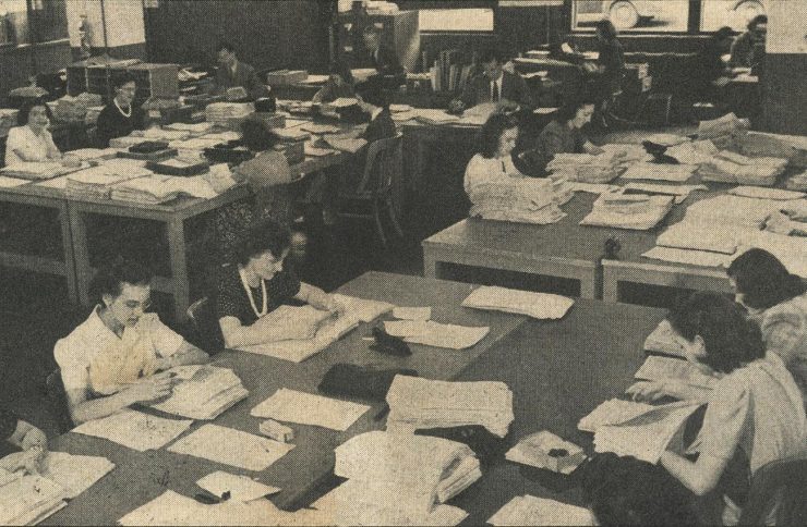 photographie tirée d’un journal montrant des douzaines de femmes au travail dans un bureau à aire ouverte