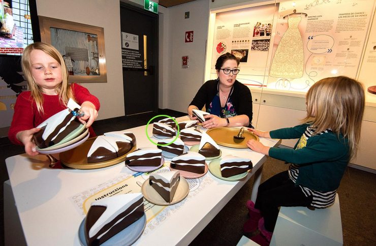 des enfants sont assis autour d’une table pleine de morceaux de faux gâteau