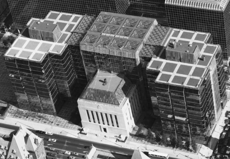 Photographie de trois tours de verre annexées à un immeuble en pierre, de forme carrée.