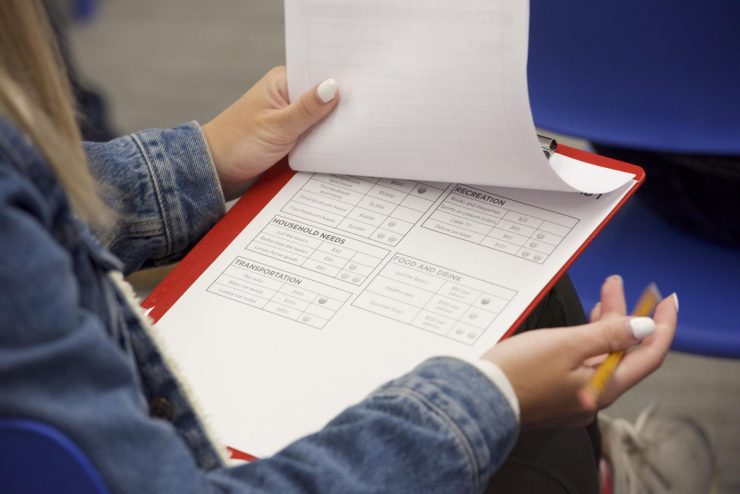 Une jeune tient une planchette sur ses genoux pour remplir un formulaire.