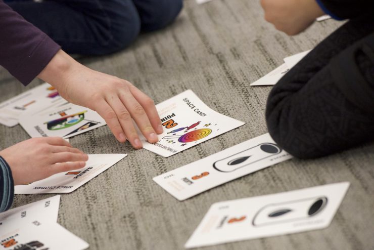 Des mains d’enfant déposent des cartes de jeu colorées avec des dessins.