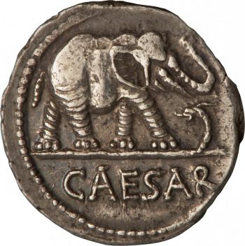 Ancienne pièce de monnaie circulaire sur laquelle est représenté de profil un éléphant, la trompe levée, piétinant un serpent. 