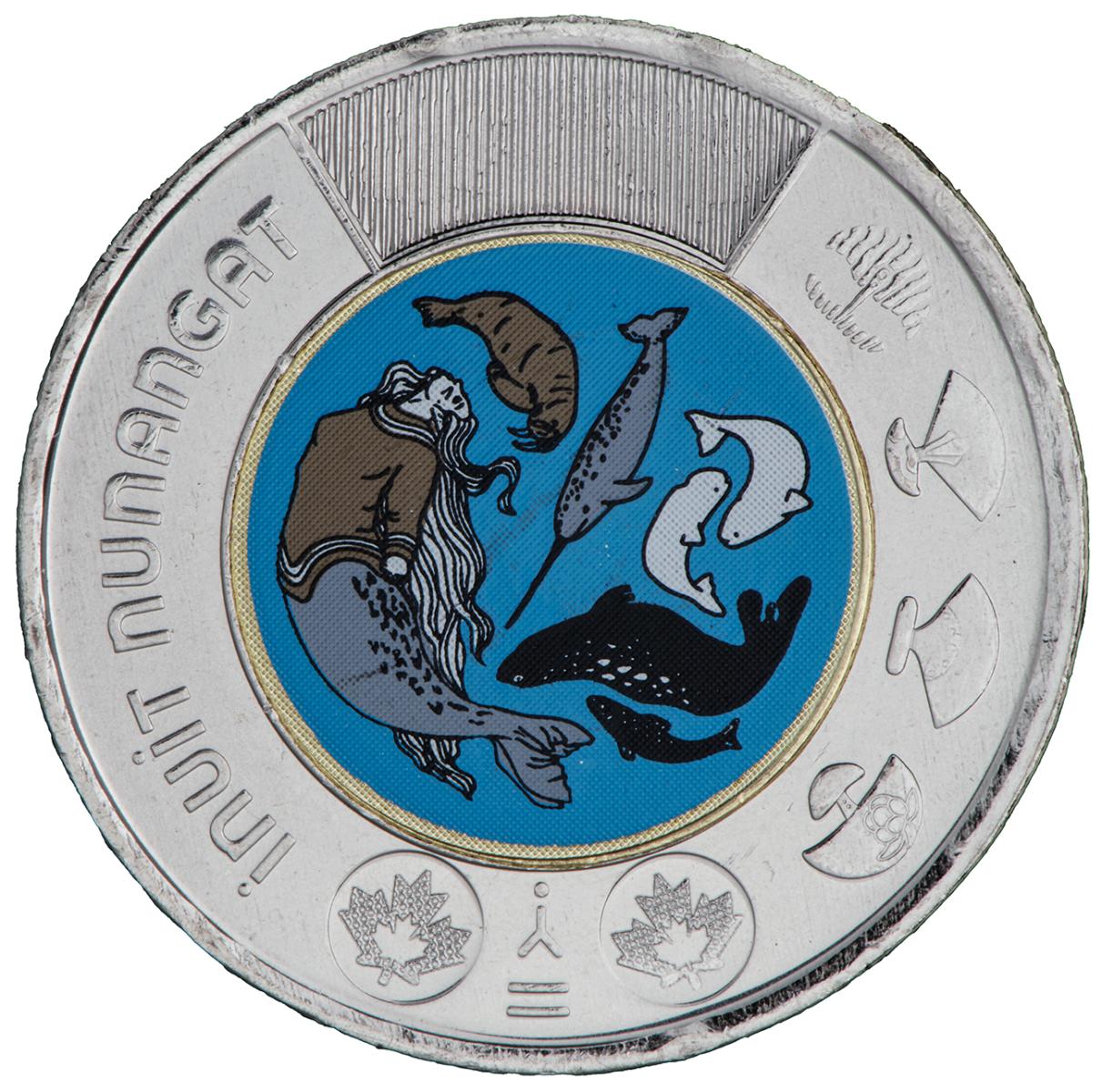 Pièce de monnaie, tour argenté orné de symboles culturels, centre illustré d’une image colorée de divers types de baleines. 