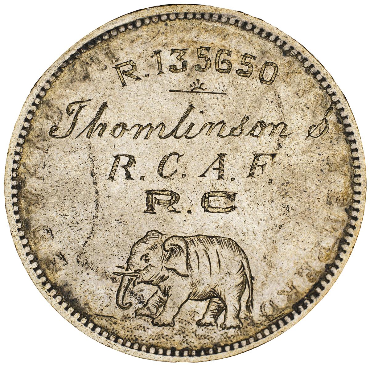 Pièce d’argent polie sur laquelle sont gravés le nom d’une organisation militaire et un éléphant.