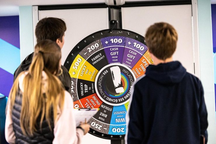 Faire tourner la roue Deux personnes tenant des planchettes font tourner une grande roue colorée.